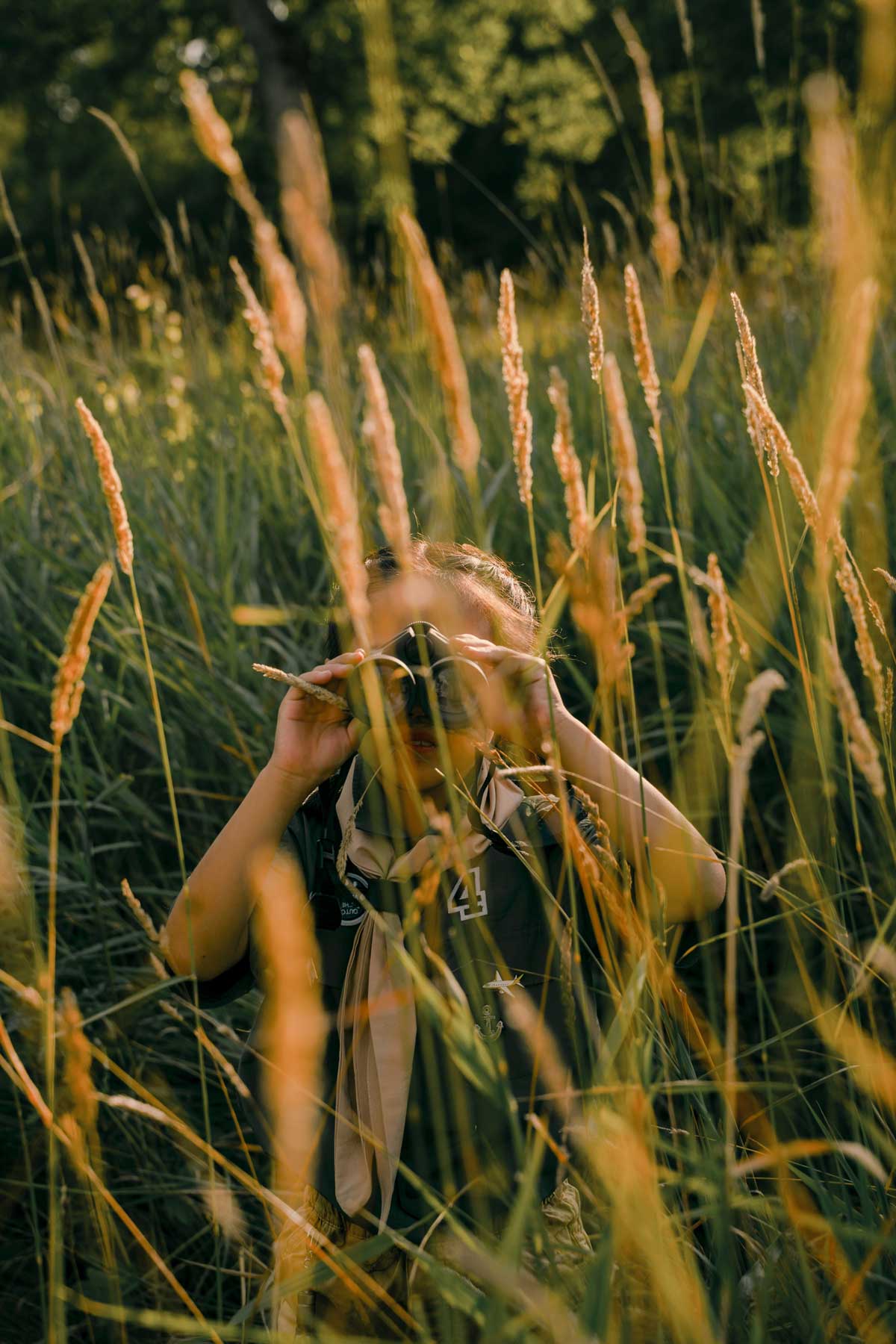 A young girl looks through binoculars to find an opportunity in the field